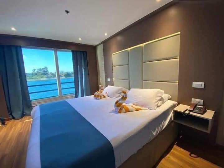 Double cabin with blue bedding, towel swans and a wide Nile-view window