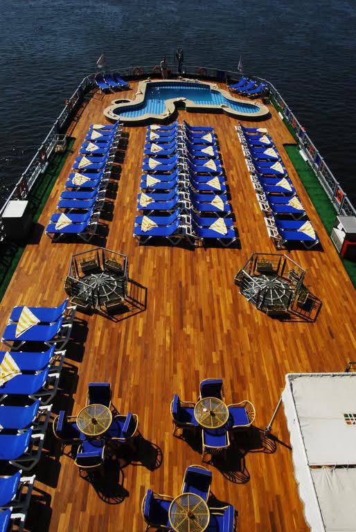 Overhead view of a wooden sundeck with blue loungers and a pool